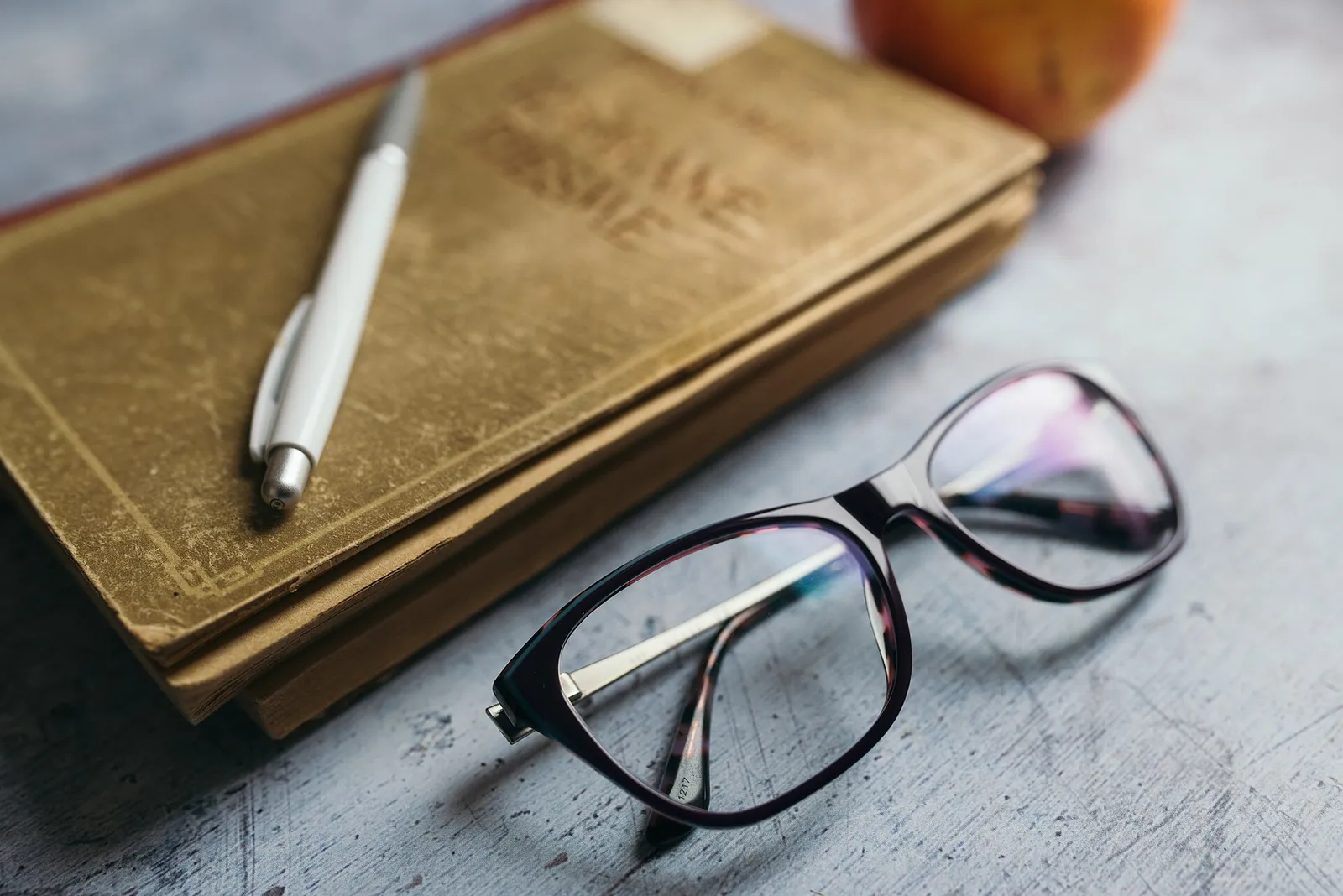 Mi lectura: Reading materials on a desk with glasses a pen and an apple nearby